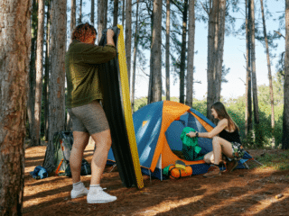 couples in the forest pitching their tent in the campsite