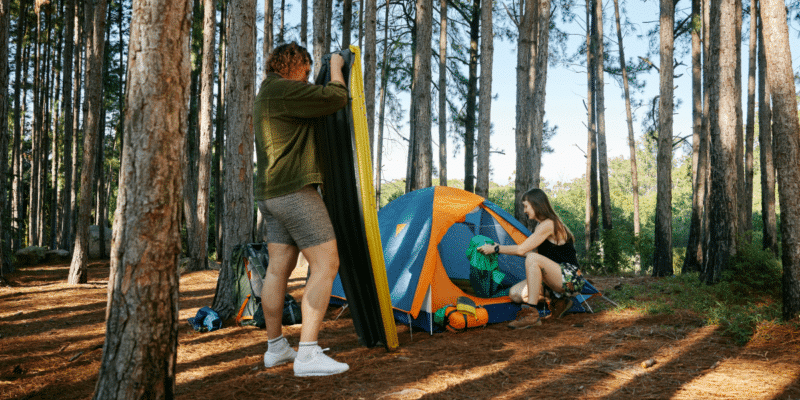 couples in the forest pitching their tent in the campsite