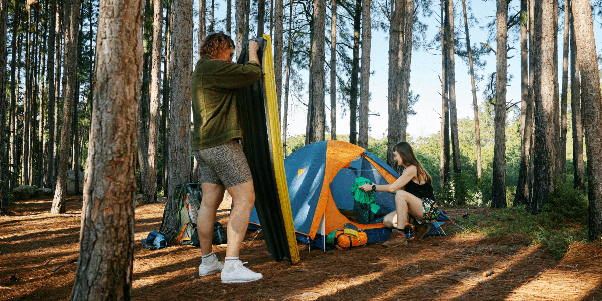 couples in the forest pitching their tent in the campsite