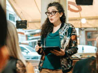 woman public speaker wearing an eyeglasses with an iPad on her hand